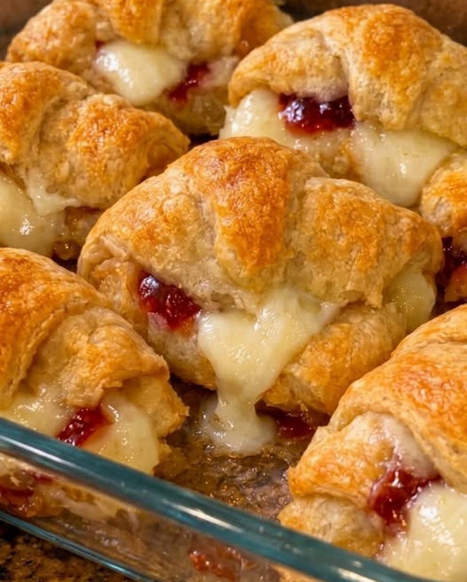 Cranberry brie crescent rolls with melted brie and cranberry sauce in a glass baking dish